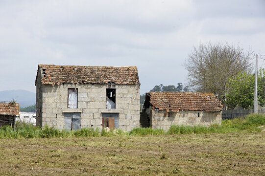 Abandoned rural stone houses showing decay in a field. Portugal - Norte