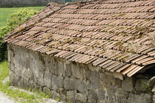 Old rural stone building with weathered roof tiles. Portugal - Norte