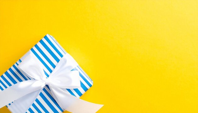 Striped gift box with ribbon on yellow background