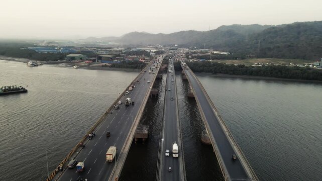 Aerial drone view of the Vasai Creek Bridge in Mumbai, India, spanning across the water and connecting key suburban regions. The scene captures vehicles moving along the bridge.
