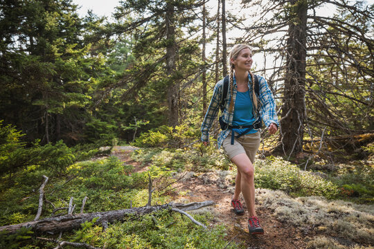 Happy woman with backpack hiking in a forest, Maine