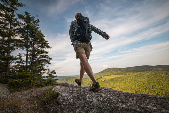Hiker with backpack walks along scenic mountain ridge, Maine.