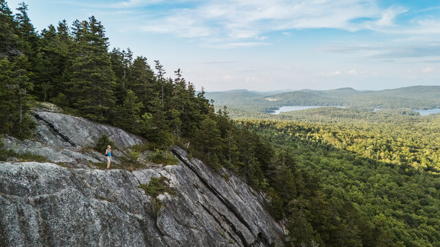 Woman enjoys view from a scenic mountain ledge near Bangor, Maine.