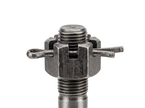 Steel castle nut bolt pin mechanical fastener assembly secured with split cotter pin on threaded screw, industrial engineering hardware component isolated on dark background for safety concept.