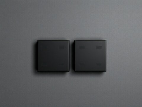 Two modern matte black square light switches on a dark grey wall