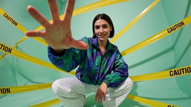Woman holding hand up in front of caution tape, playful pose