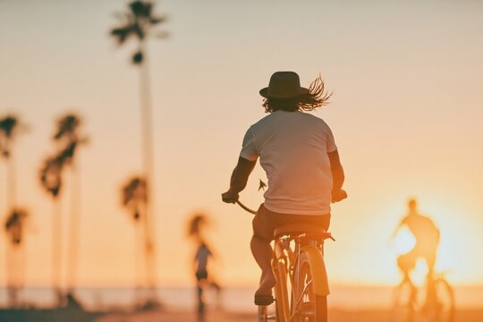 Biking along the beach at sunset with palm trees in the background