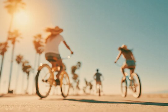 Cyclists ride bikes along a sunny beachfront path with palm trees in the background during the late afternoon