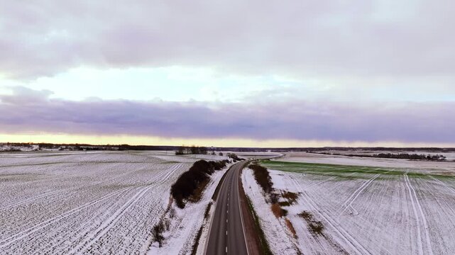 Snowy Road in Tukums Latvia - Aerial View of Winter Fields Beneath Stormy Clouds