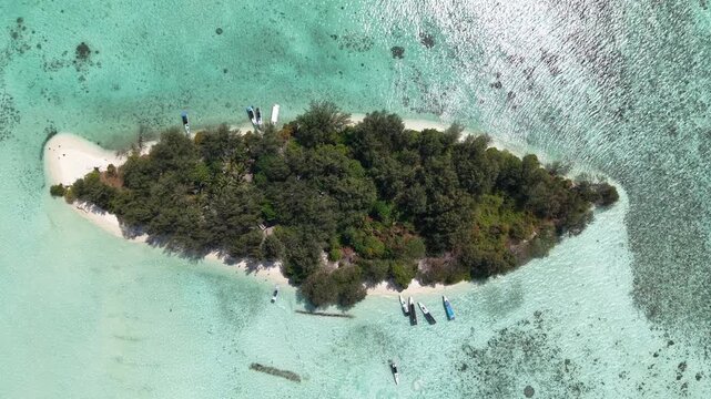 Stunning aerial footage of Cemara Kecil Island, Karimunjawa Indonesia with crystal clear water, white sandy beach, lush pine trees and tropical paradise scenery.