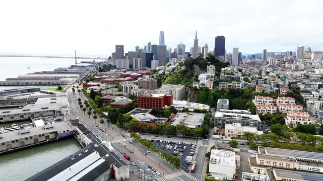 Aerial drone view of San Francisco, California, showing the downtown skyline, Embarcadero waterfront, Bay Bridge, city streets and San Francisco Bay. Wide cinematic establishing footage of the urban