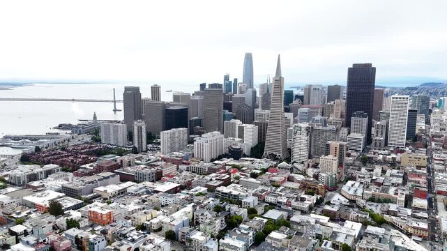 Aerial drone view of San Francisco, California, showing the downtown skyline, Embarcadero waterfront, Bay Bridge, city streets and San Francisco Bay. Wide cinematic establishing footage of the urban
