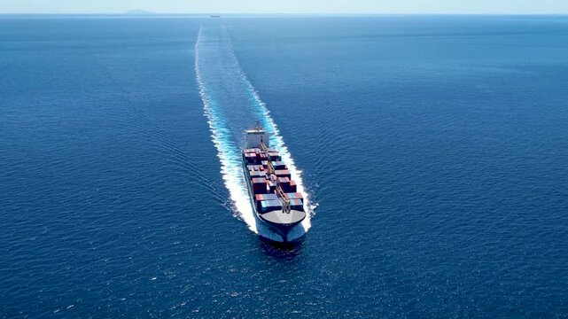 High aerial view of a loaded container cargo ship traveling over the ocean with high speed