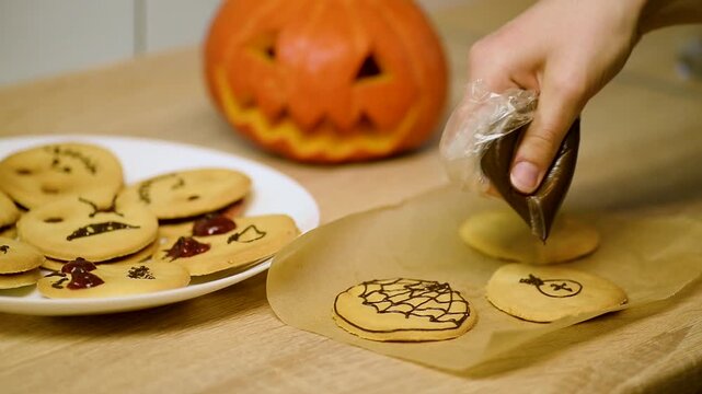 Drawing a chocolate spider character on a baked shortbread cookie