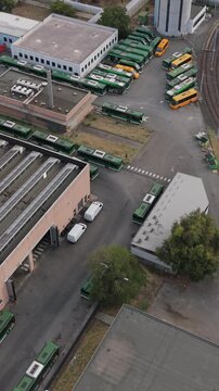 Aerial view of a green electric bus arriving at a charging depot in Milan, Italy, highlighting electric public transport, EV infrastructure and sustainable mobility.