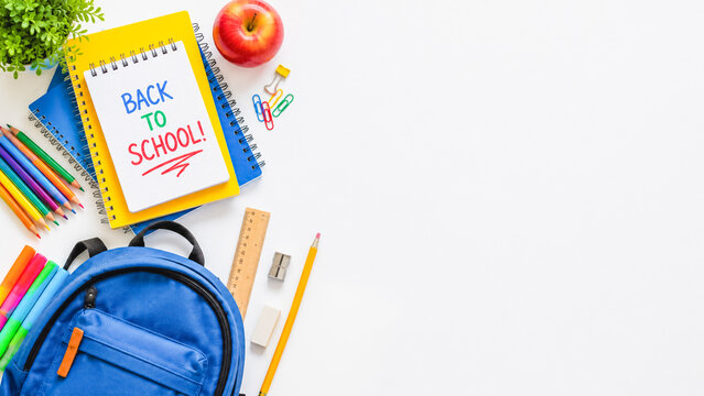 Back to school themed composition with notebooks, backpack, pencils, ruler, apple, and office supplies organized around empty space for text.