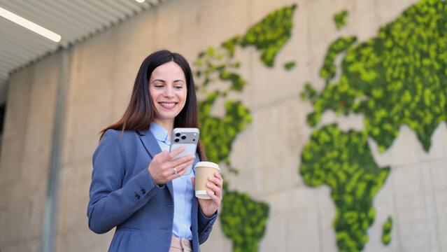 Businesswoman checking smartphone with green world map