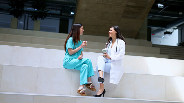 Two smiling female doctors having a coffee break and talking