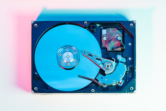 opened computer hard disk drive HDD internal components focusing on plattered disk and actuator read write head arm as a conceptual metaphor for cyber security big data cloud computing infrastructure 