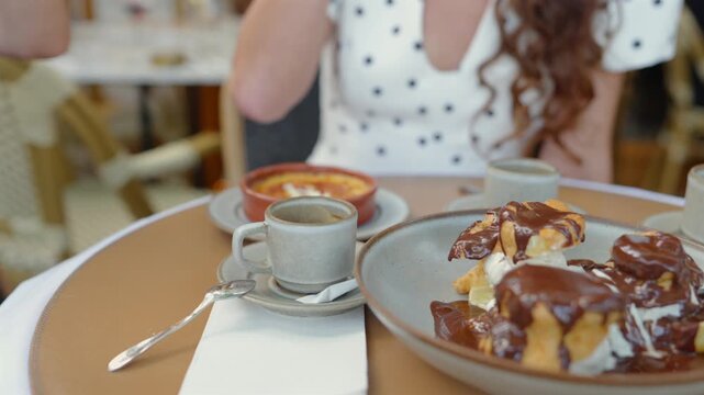 Traditional profiteroles with vanilla ice cream, chocolate sauce and coffee in Paris
