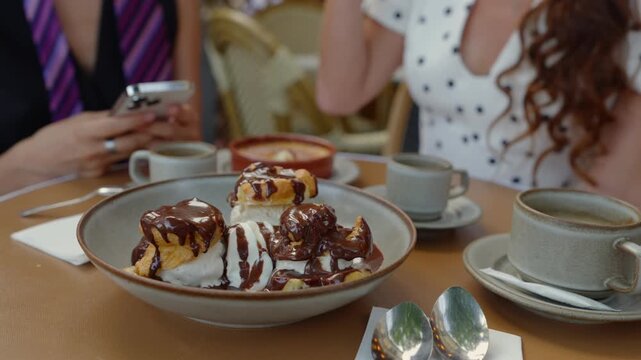 Profiteroles with chocolate sauce, vanilla ice cream and coffee at a French cafe