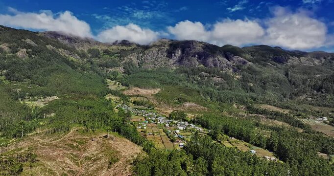 Aerial view of the lush green tea plantations of Munnar, Kerala, covering rolling hills under a bright blue sky with scattered clouds, the scenic beauty of this popular hill station in South India.