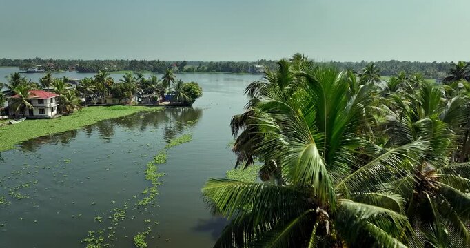 Aerial view of the Alleppey backwaters in Kerala, featuring lush green islands,  village houses, and calm waterways, showcasing the scenic beauty of this popular tourist destination in South India.