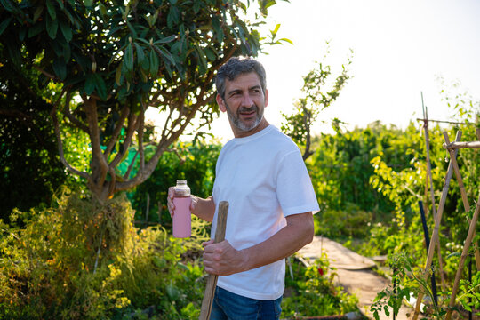Man holding water bottle working in garden