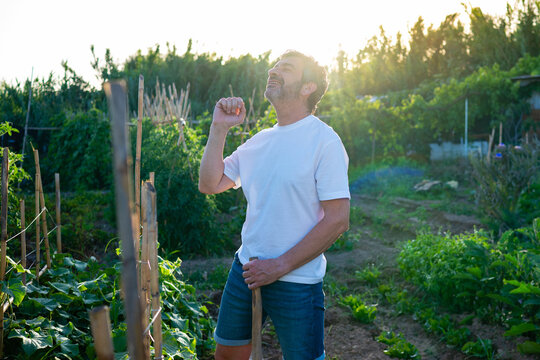 Happy man enjoying success and satisfaction in organic garden