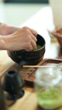 Traditional Japanese Matcha Tea Ceremony Preparation with Chasen Whisk in Black Ceramic Bowl