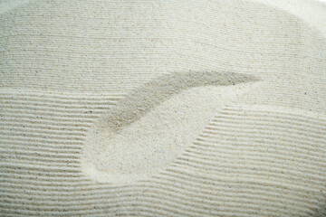 Close-up of raked white sand with a smooth curved stroke, representing mindfulness, Zen philosophy,...