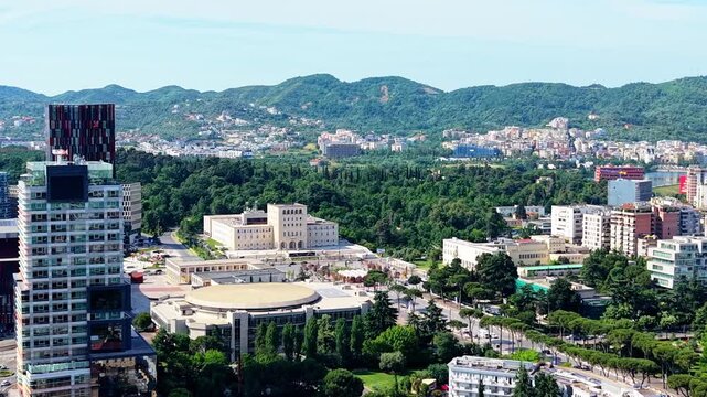 Aerial view of the modern cityscape of Tirane, featuring the Pyramid of Tirana, surrounding green parks, and urban architecture under a clear sky in Tirane, Tirana County, Albania.