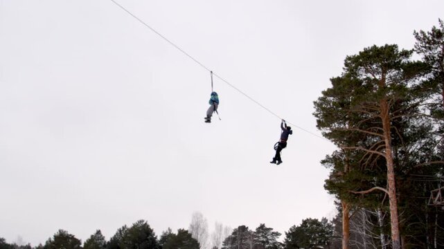 Zip-line ropes in winter park. Instructor helps child zip-lining on long thick rope in cold winter adventure rope park. Holiday adventures