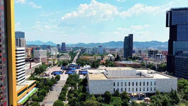 Aerial view of Skanderbeg Square surrounded by modern high-rise buildings and lush green trees in the city center Tirana, Qarku i Tiranes, Albania.