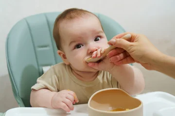 Baby at mealtime: a moment of independent feeding in a high chair. © olgasparrow