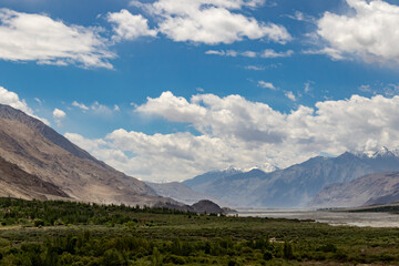 Fototapeta premium Mountain valley under blue sky with white clouds
