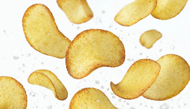 Crispy potato chips falling with sea salt crystals against a clean white background.