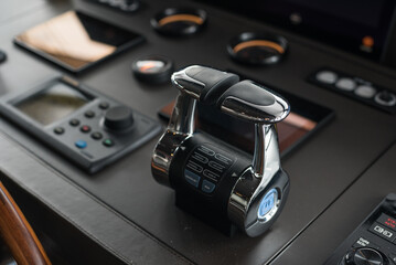 Wheelhouse, bridge of a modern new build superyacht, with wooden wheel, throttle controls, radar, auto-pilot, navigation and other control panels © lupiphoto