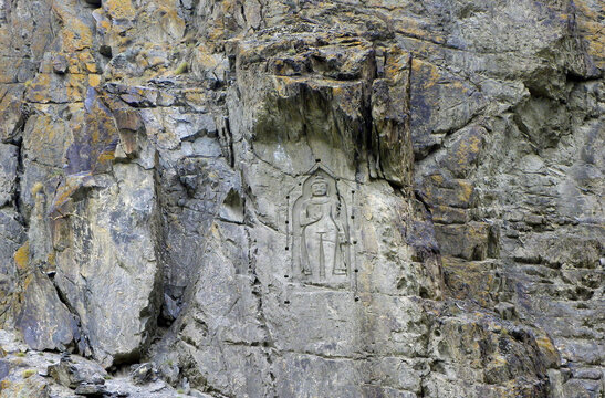 View of the ancient rock-carved Kargah Buddha relief set into a rugged cliff face in Hunza Nagar, Gilgit-Baltistan, Pakistan.