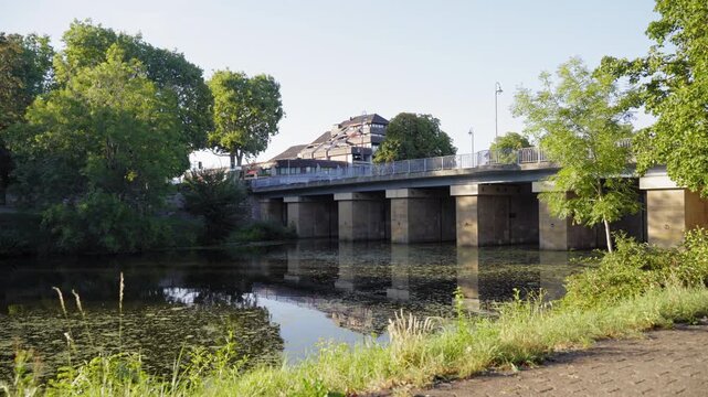 Urban bridge crossing a calm river surrounded by green trees and vegetation in Saarlouis Germany