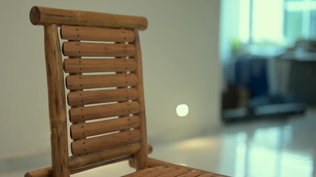A close-up view of a handcrafted vintage wooden lounge chair featuring a slatted backrest, placed in a minimalist indoor setting.