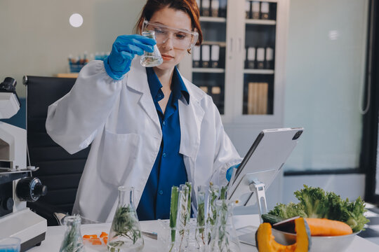 Scientists in lab coats work with plants in a modern lab, focusing on research and experimentation under bright, sterile conditions.