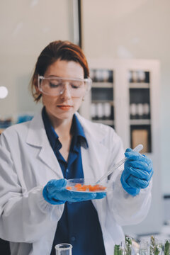 Scientists in lab coats work with plants in a modern lab, focusing on research and experimentation under bright, sterile conditions.
