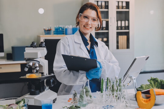 Scientists in lab coats work with plants in a modern lab, focusing on research and experimentation under bright, sterile conditions.