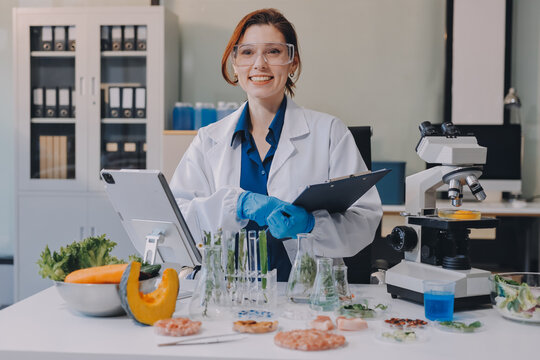 Scientists in lab coats work with plants in a modern lab, focusing on research and experimentation under bright, sterile conditions.