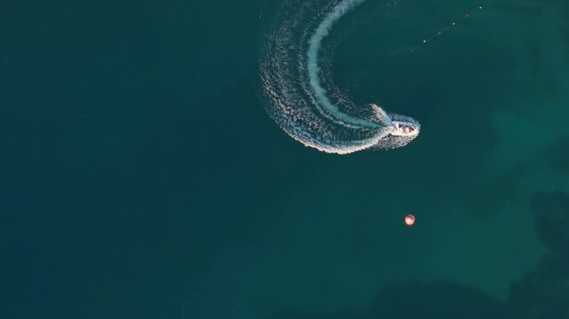 Aerial view of a small motorboat leaving a white wake in the turquoise waters of the Ionian Sea near Porto Palermo, Qarku i Vlores, Albania.