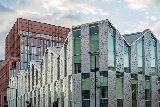 View of the modern glass and metal facade of King's Cross St. Pancras station with its intricate patterns, set against a tall red brick building London, England, United Kingdom.