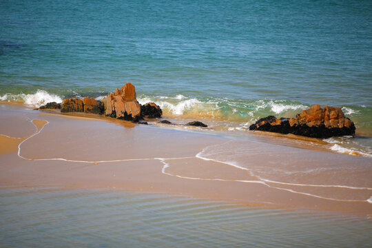 Turquoise ocean waves washing over rocks on a sandy beach
바위와 파도가 있는 해변