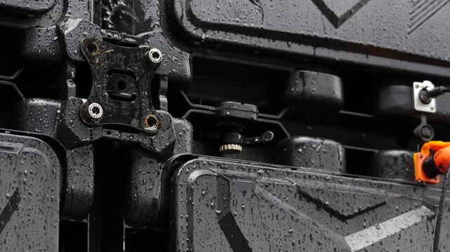 Wet black electrical junction box under heavy rain. Water droplets on exposed connections create critical short circuit hazard, potential fire danger, and severe outdoor safety risk. vertical 4k shot