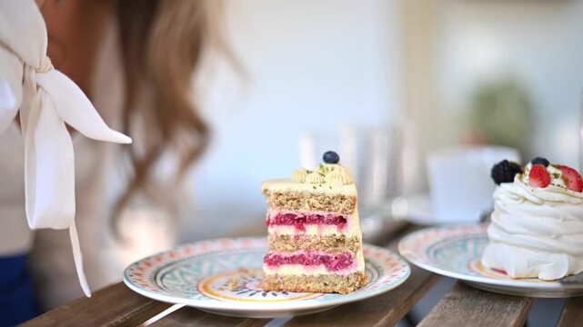Woman eating delicious layer cake with berries at outdoor cafe table.